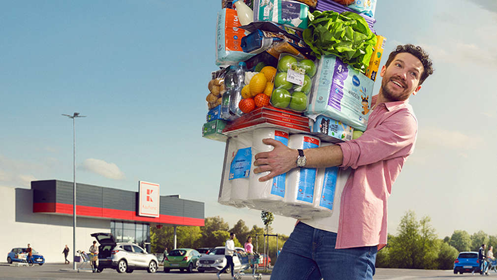 Muž nese náruč zboží z Kauflandu