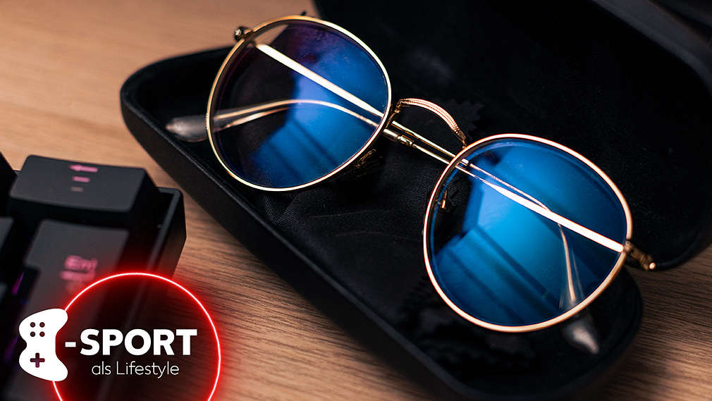 Eine Brille mit Blaulichtfilter liegt auf einem Schreibtisch neben einer Gaming-Tastatur