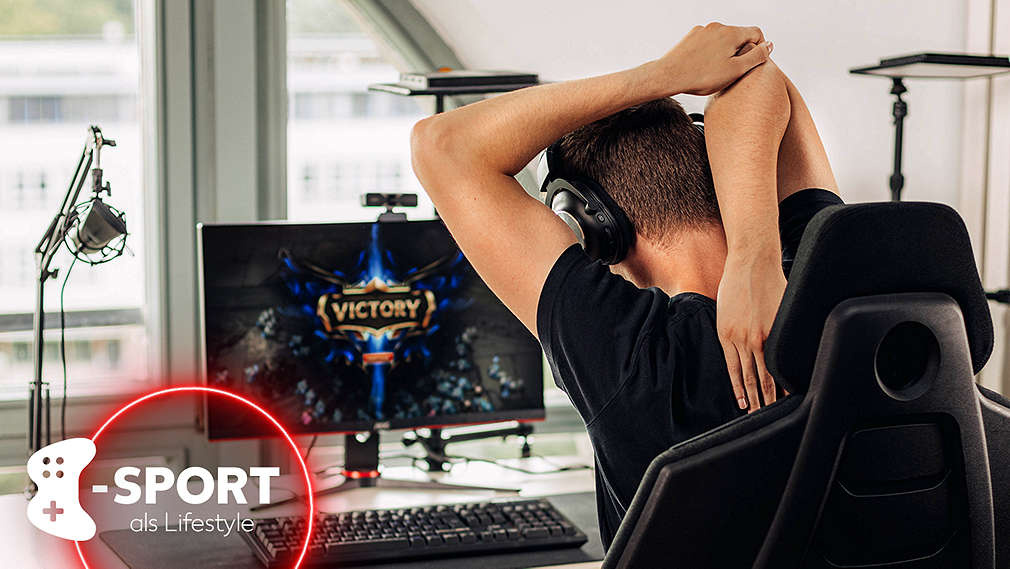 Gamer sitzt in einem Gaming-Stuhl am Schreibtisch vor einem Bildschirm und dehnt die Arme über dem Kopf 