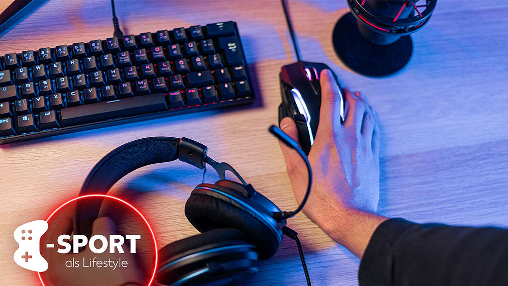 Verschiedene Gaming-Gadgets wie eine Gaming-Tastatur, -Maus sowie ein -Headset liegen auf einem Gaming-Tisch