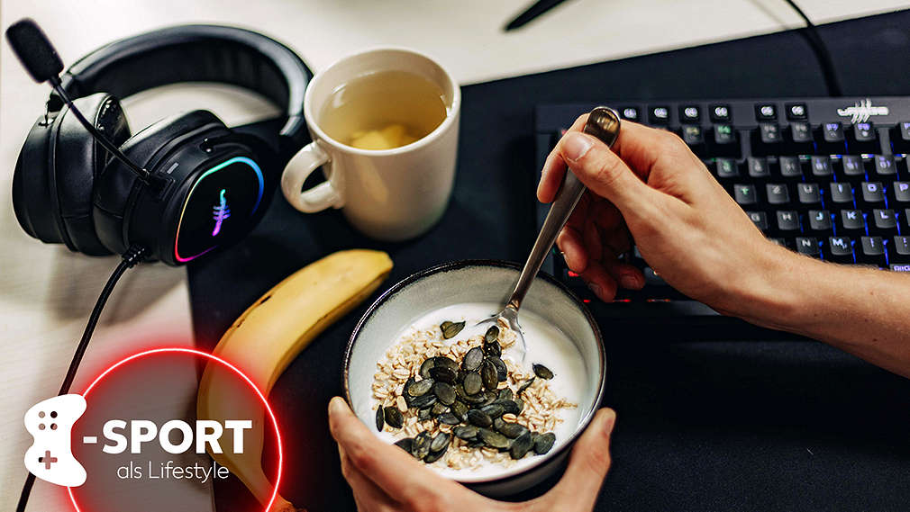 Eine Person im Anschnitt isst Joghurt mit Müsli aus einer Schale, daneben liegt eine Banane, ein Gaming-Headset und eine Gaming-Tastatur