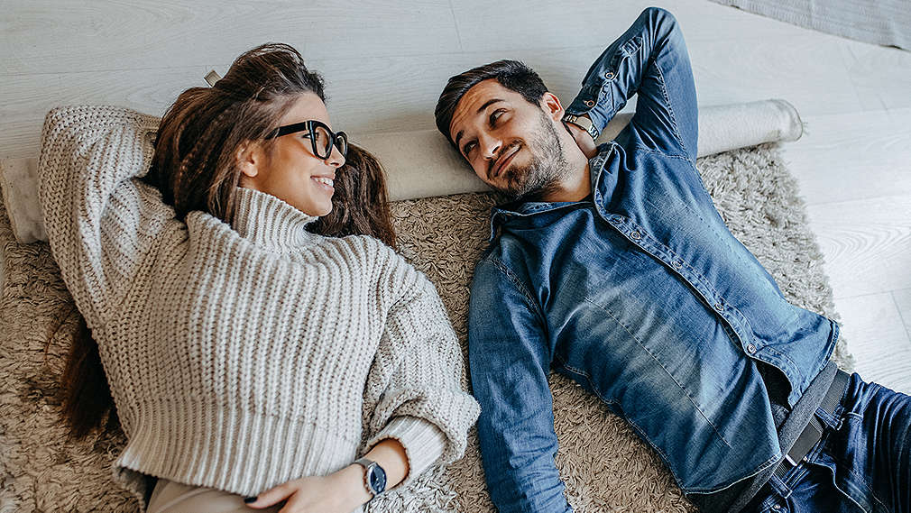 Paar sitzt lachend auf Sofa 