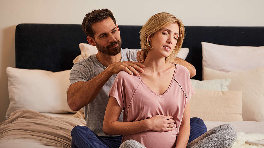 Mann massiert schwangere Partnerin