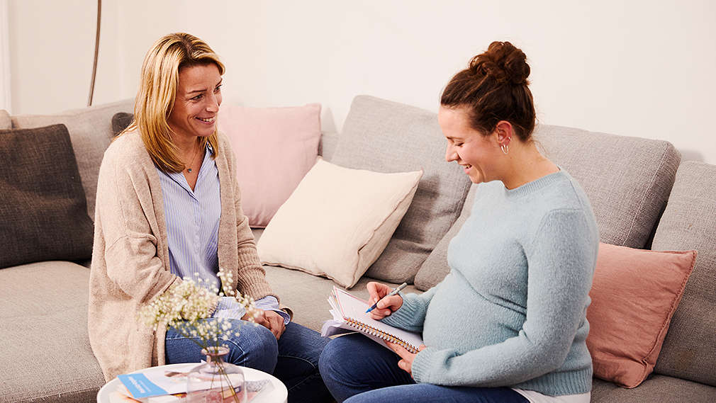 Schwangere Frau spricht mit Hebamme