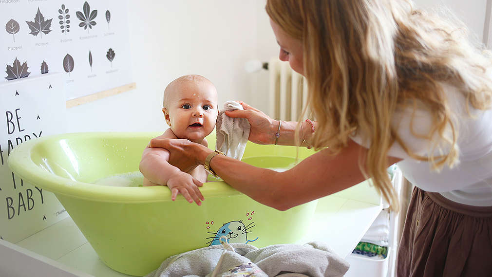 Baby wird in Badewanne von Mutter gebadet