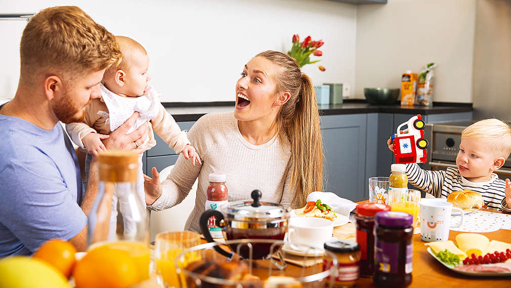 Eltern mit Baby und Kleinkind am Frühstückstisch