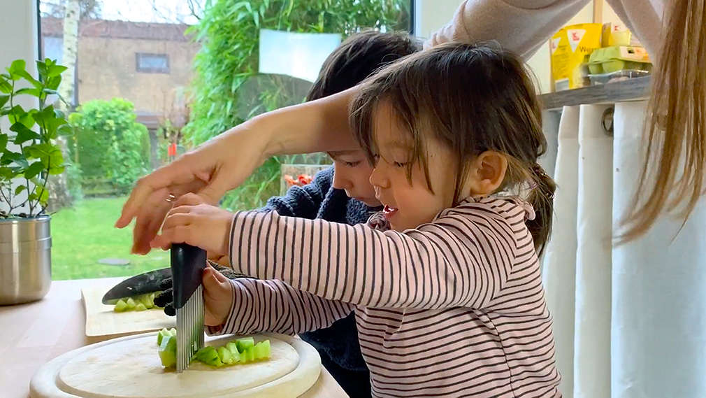 Kinder und Mutter beim Gemüseschneiden