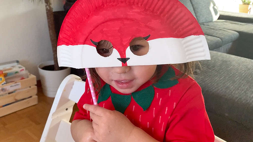 Kind hält eine Faschingsmaske vor sein Gesicht