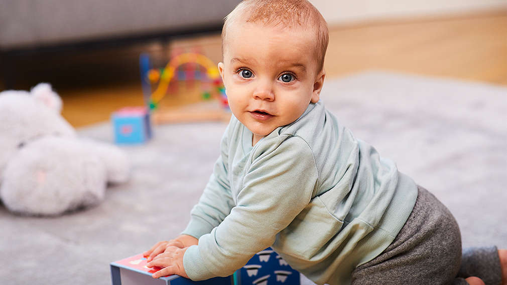 Baby versucht aufzustehen und stützt sich ab