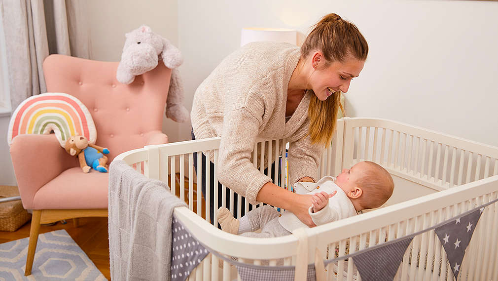 Mutter legt sein Baby ins Kinderbett