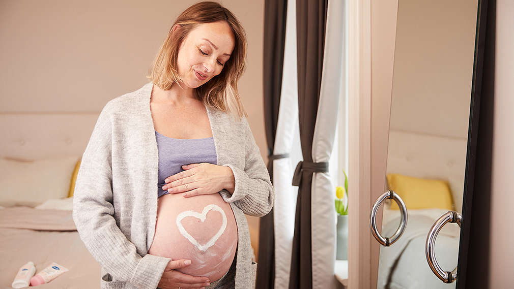 Eine schwangere Frau vorm Spiegel im Bad
