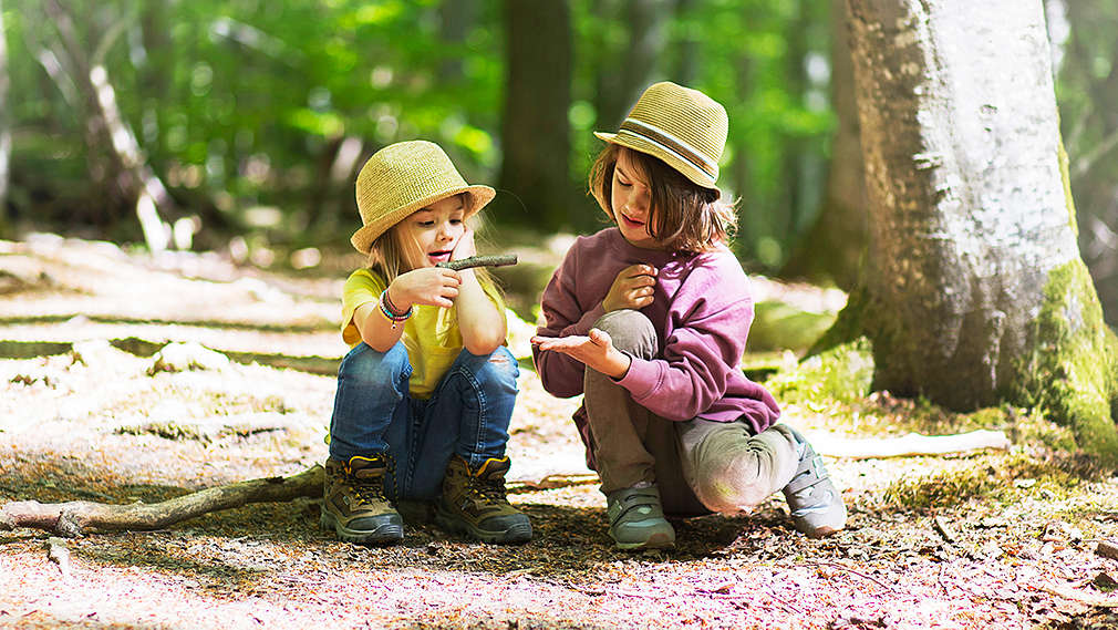 Kinder sitzen auf dem Boden im Wald