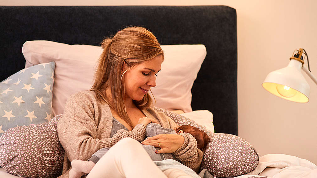 Mutter stillt Baby im Bett