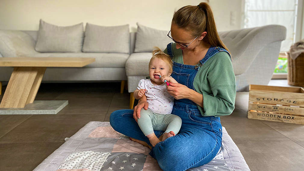 Baby sitzt bei der Mutter auf dem Schoß
