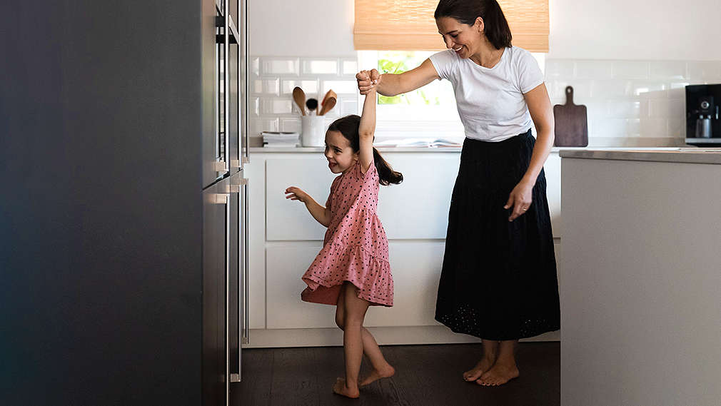 Mutter tanzt mit Tochter in der Küche