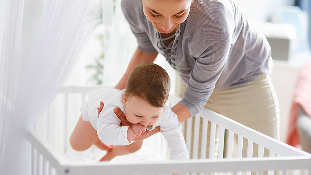 Mutter legt ihr Baby ins Babybett