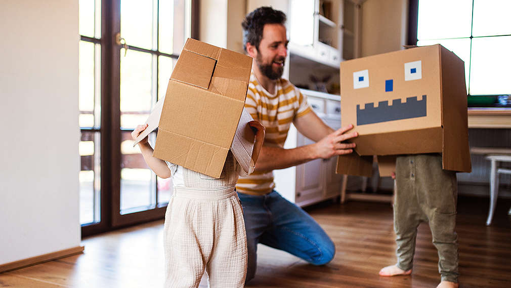 Vater und Kinder spielen mit Kartons