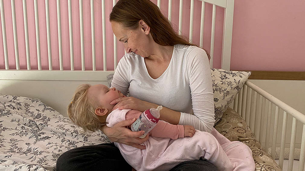 Mutter sitzt mit Baby im Bett