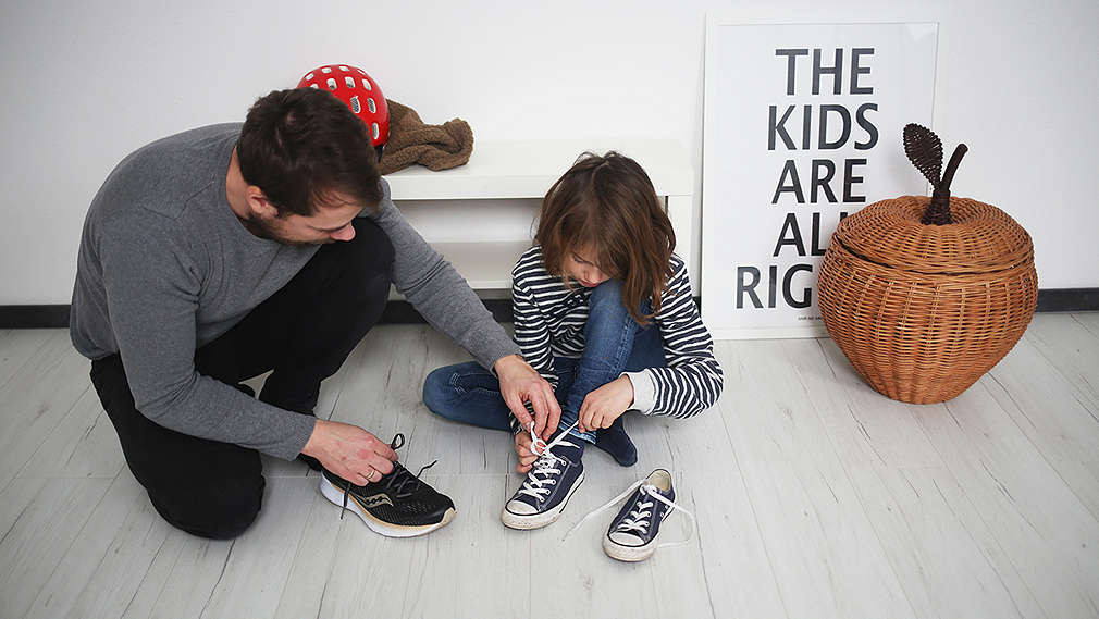 Vater und Kind binden Schuhe