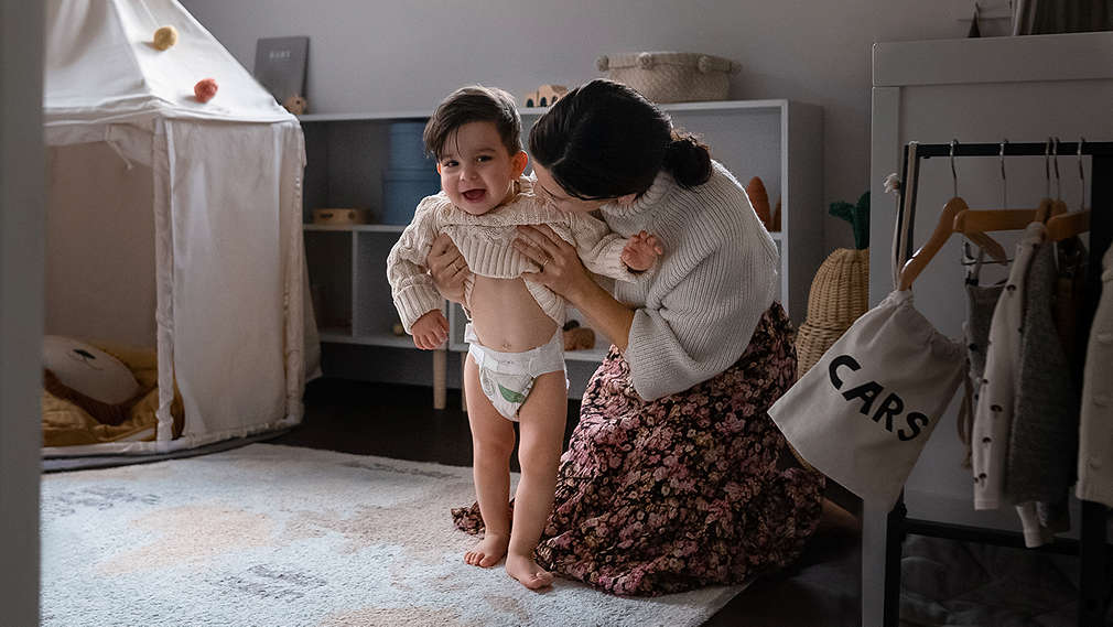 Mutter unterstützt ihr Kind beim Stehen