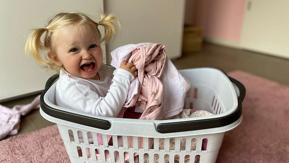 Mädchen sitzt im Wäschekorb