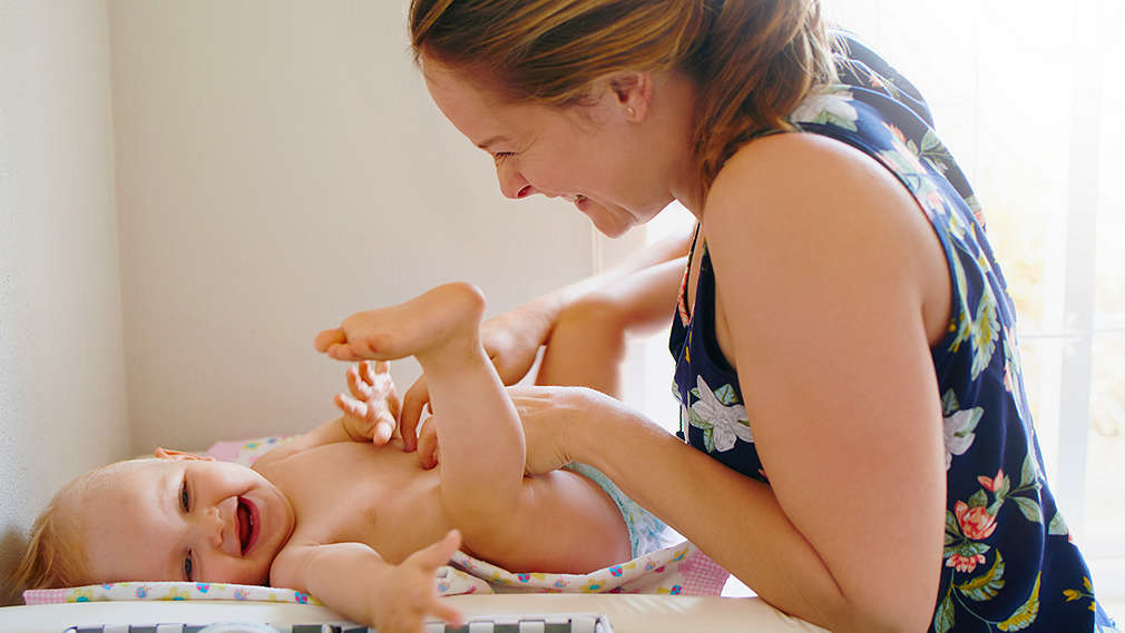 Mutter wickelt ihr Baby auf einem Wickeltisch