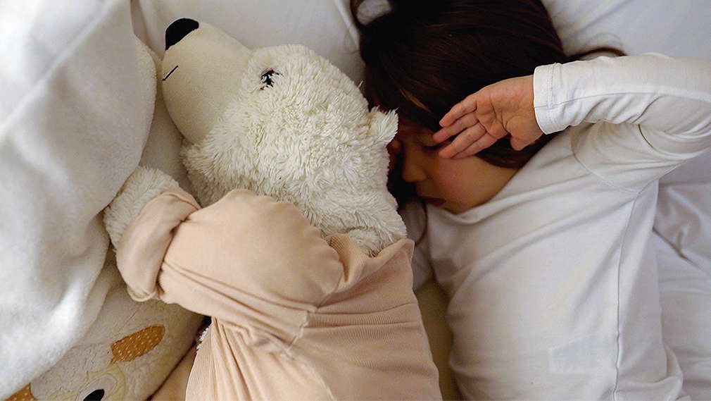 Junge mit Stofftier im Bett