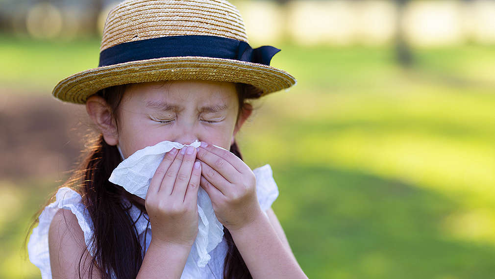 Mädchen niest ins Taschentuch