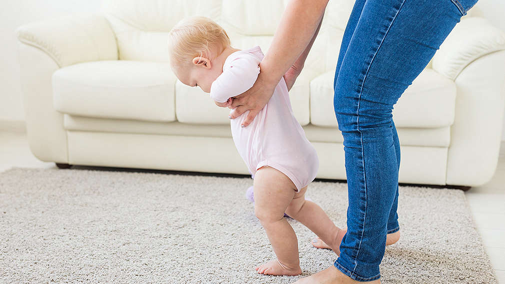 Frau greift Baby unter die Arme