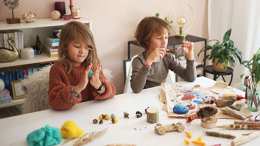 Zwei Kinder sitzen am Tisch und basteln