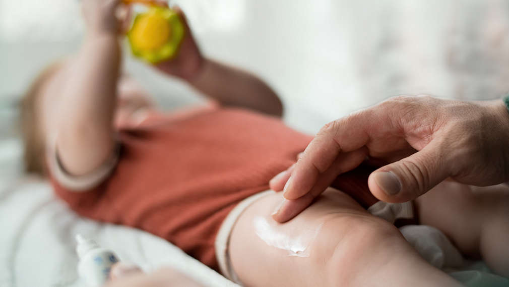 Mann cremt Babyhaut ein