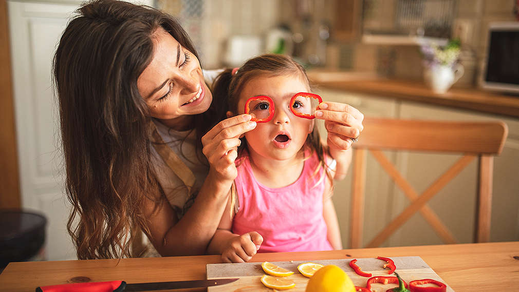Mutter hält Tochter Paprika vor die Augen