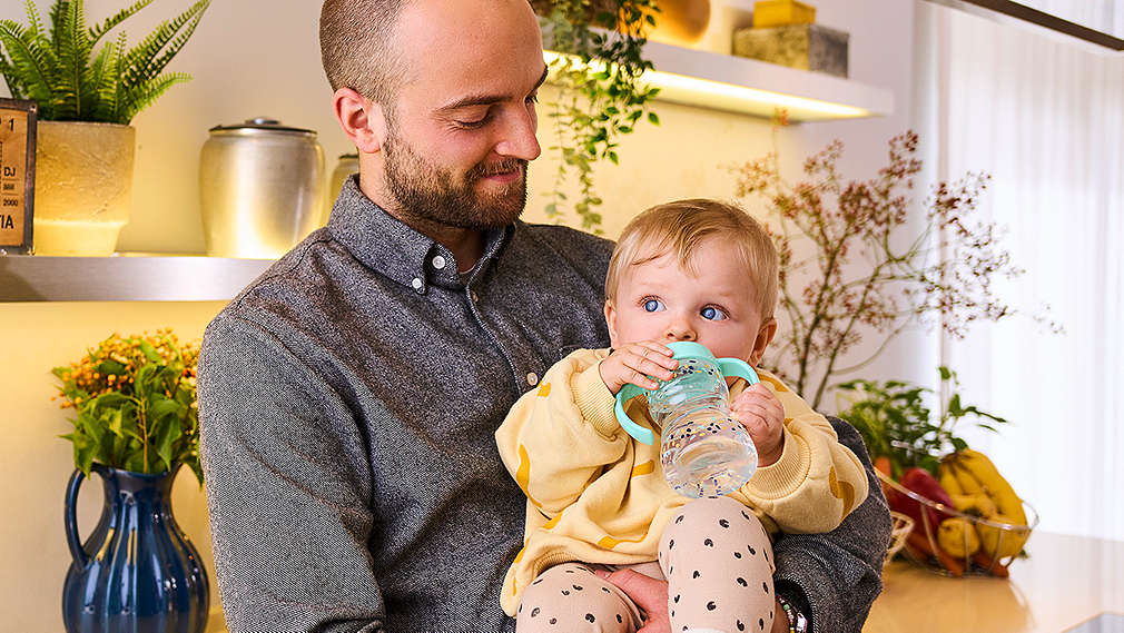 Vater hält trinkendes Kind auf dem Arm