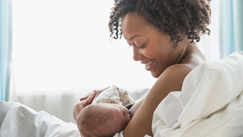 Neugeborenes trinkt an der Mutterbrust