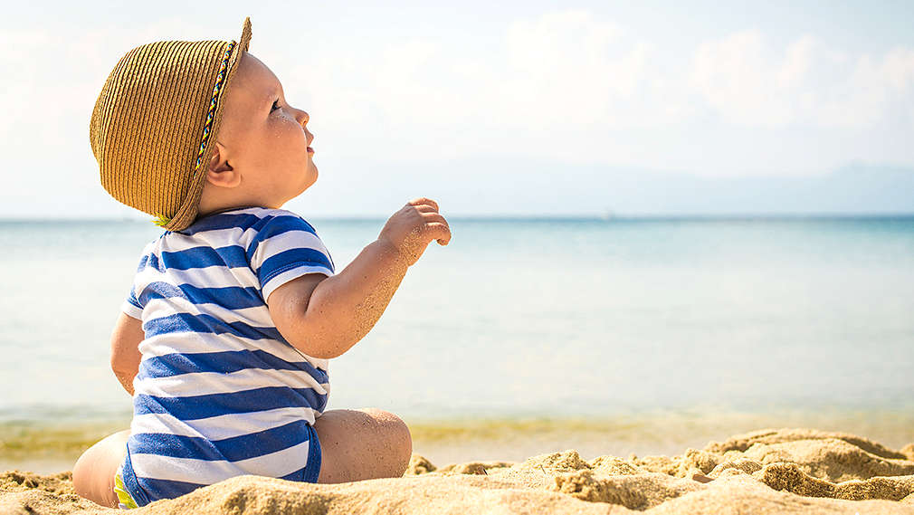 Baby sitzt am Strand