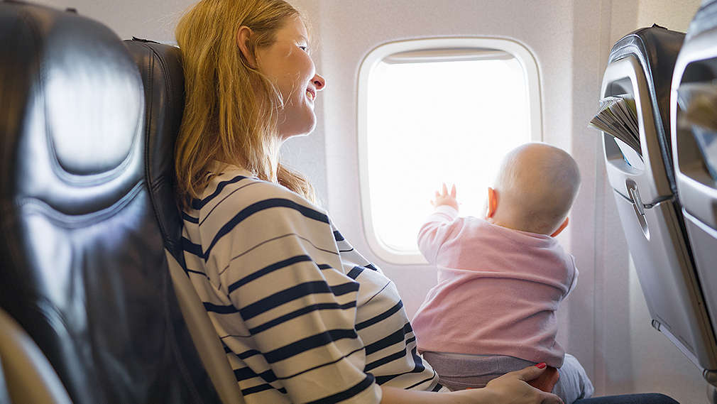 Mutter sitzt mit Baby im Flugzeug