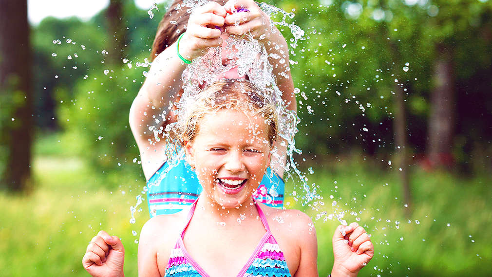 Mädchen spielen draußen mit Wasser
