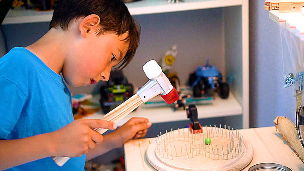 Junge hämmert Nägel in ein Brett