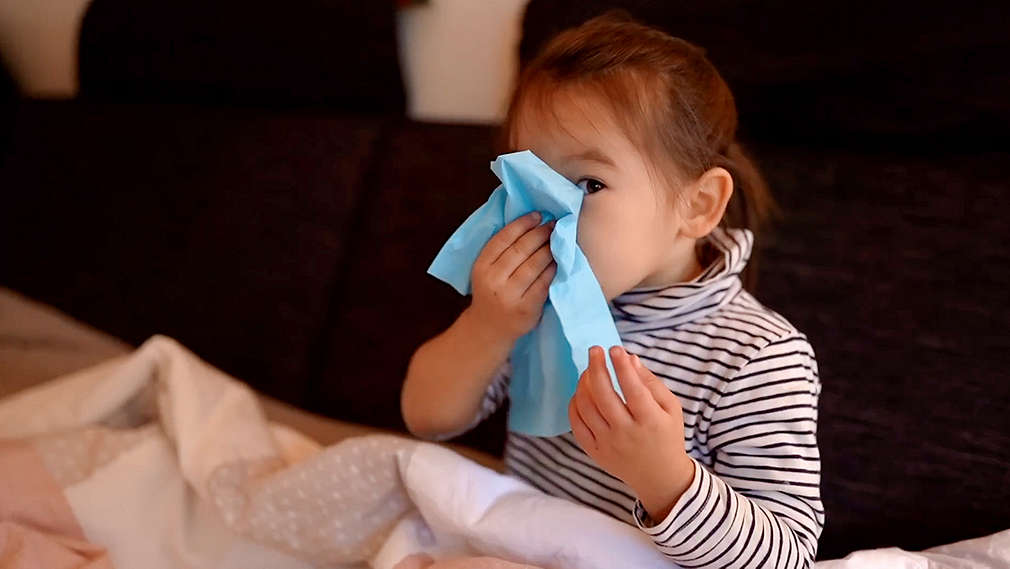 Krankes Kind putzt sich die Nase