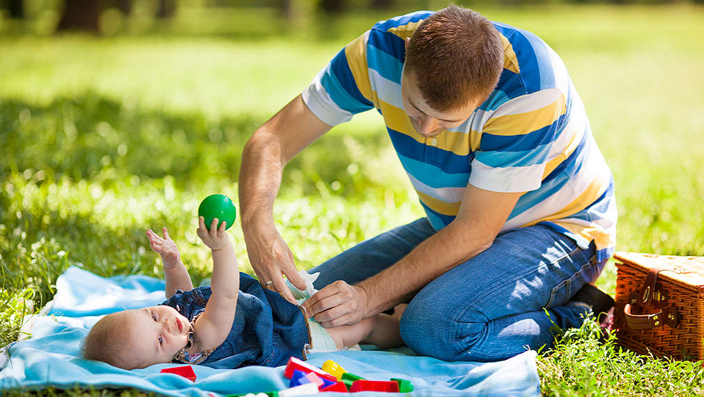 Mann wickelt Baby unterwegs