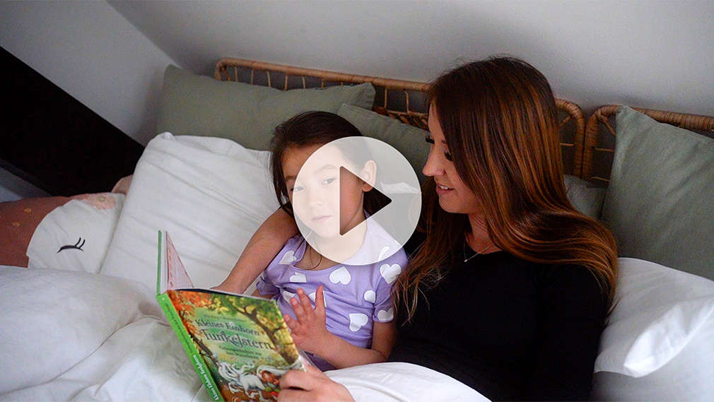Mutter und Tochter lesen im Bett gemeinsam ein Buch vor dem Schlafengehen