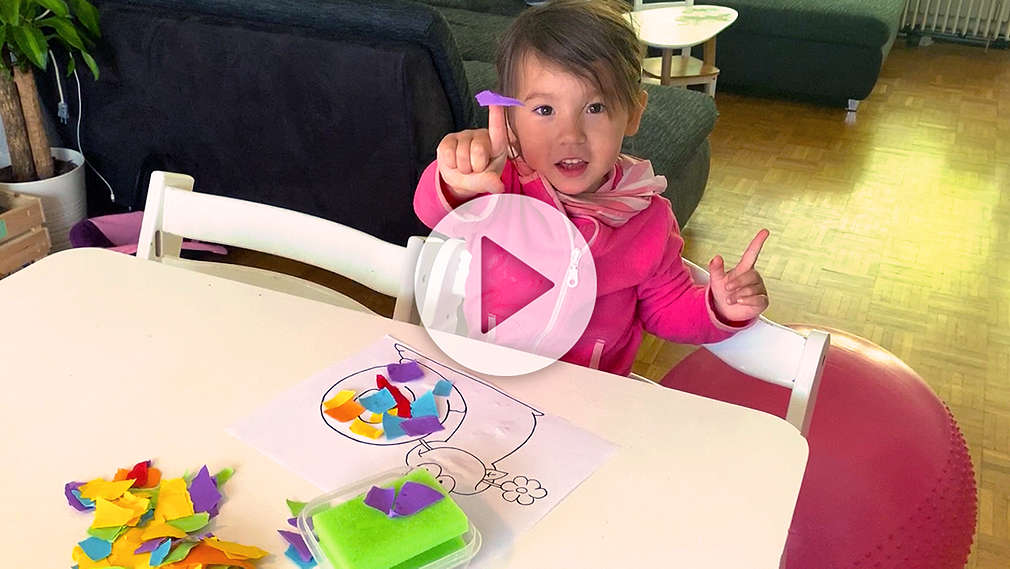 Kind bastelt ein Schnipselbild mit Schneckenmotiv