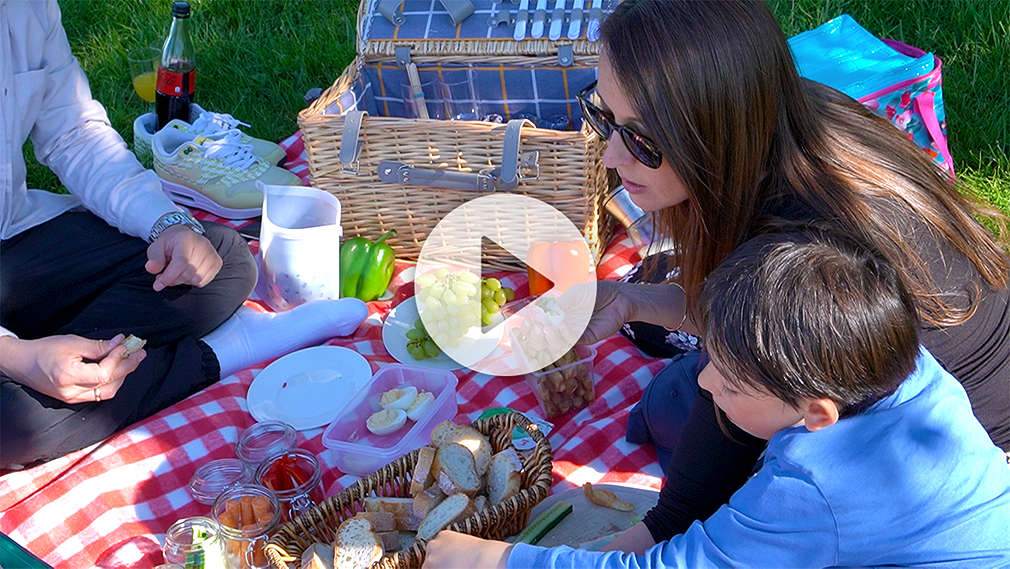 Eine Familie sitzt auf einer Decke und macht Picknick