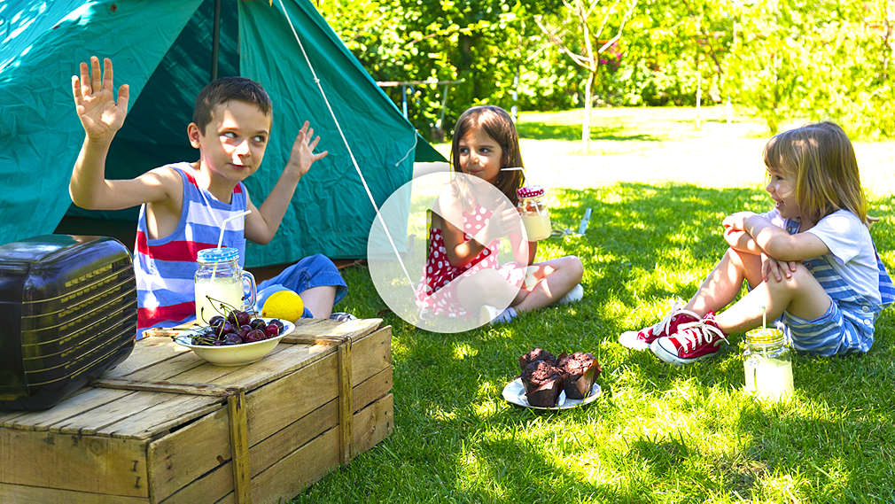 Drei Kinder sitzen vor einem Zelt