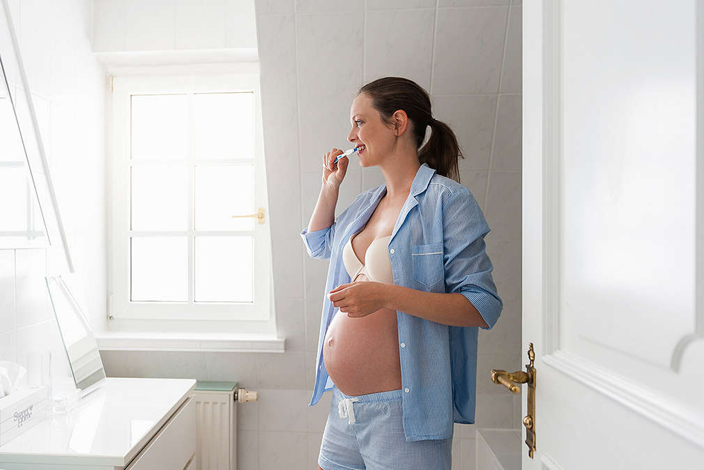 Изображение на бременна жена, която си мие зъбите