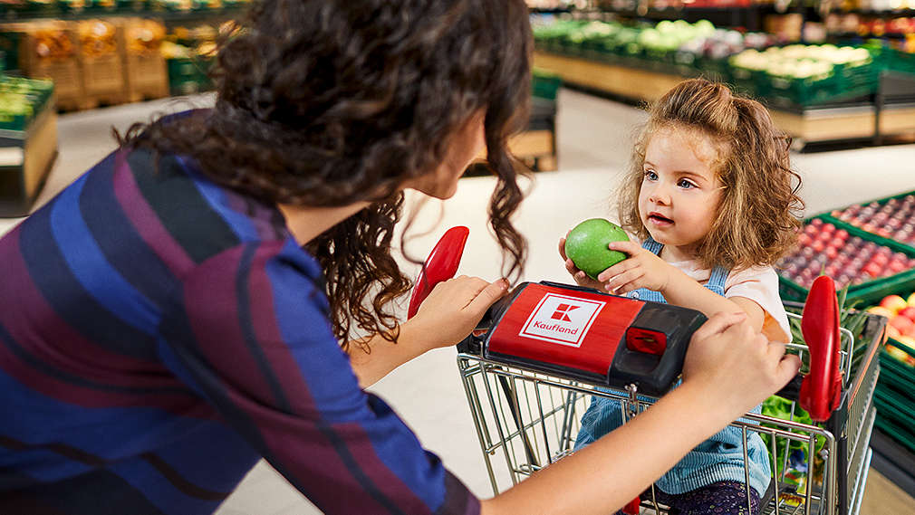 Mutter mit Tochter, die im Kaufland-Einkaufswagen sitzt