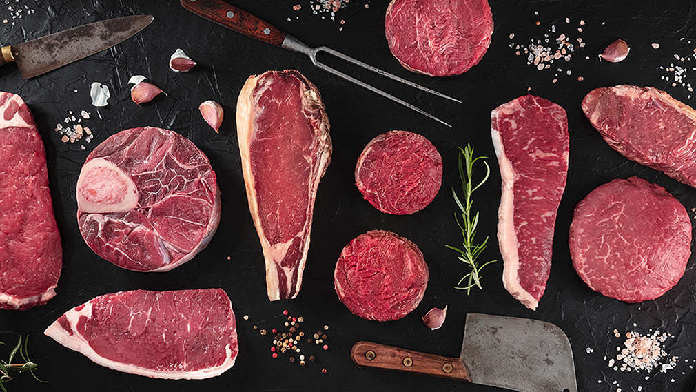 Verschiedene Fleischteilstücke auf einer Schieferplatte