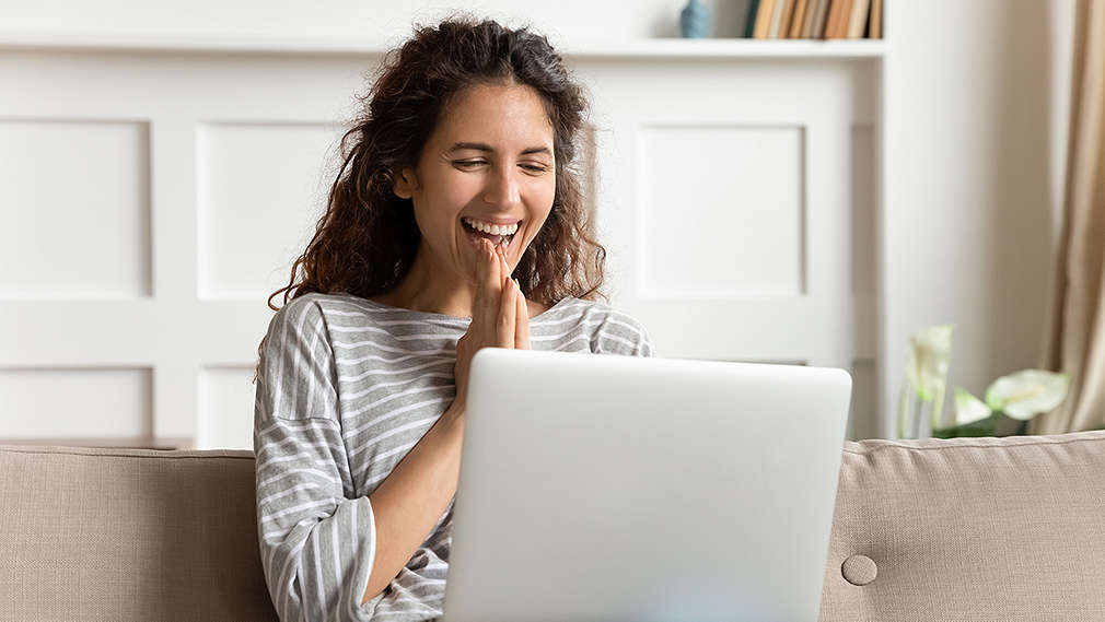  Žena sretno sjedi ispred laptopa