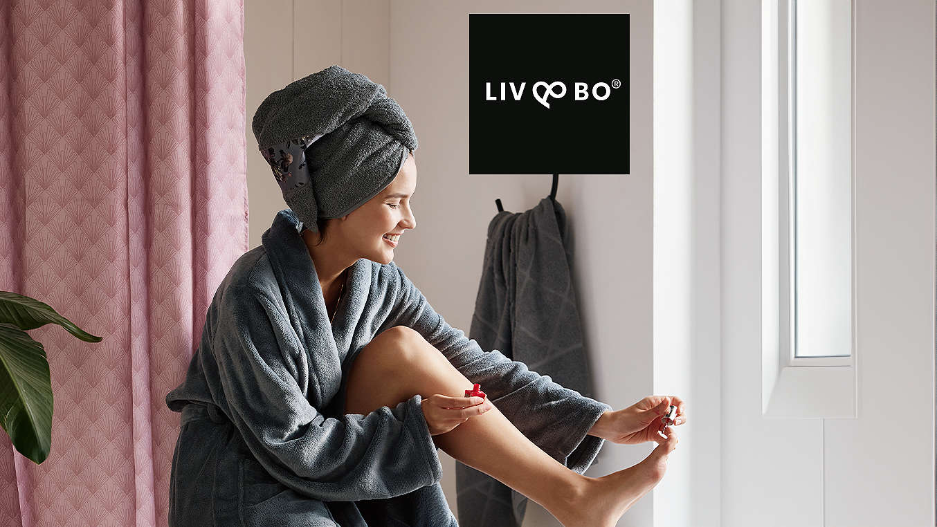 Logo: LIV&BO®; Abbildung: Frau auf Badewanne mit Bademantel und Frottier-Handtuch