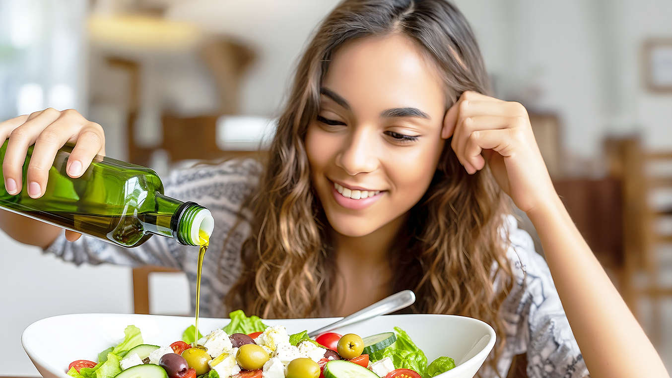 Frau gießt Öl über Salat